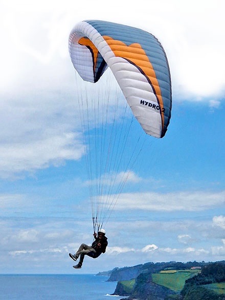 Pilot soaring under a Windtech Hydro wing above the coast