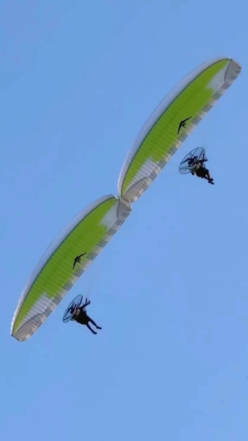Two HE paramotors flying in formation under lime wings